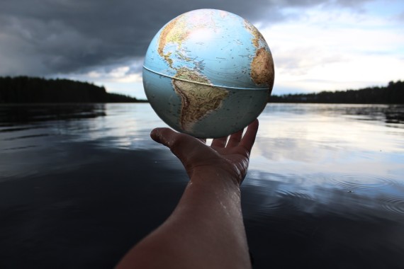 Arm outstretched over water holding globe