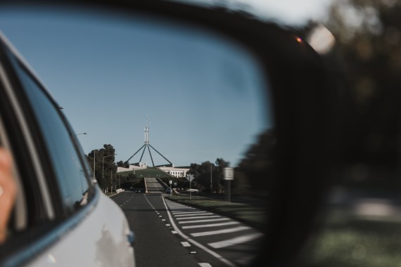 A photograph of Parliament House reflected in the rear view mirror of a car 