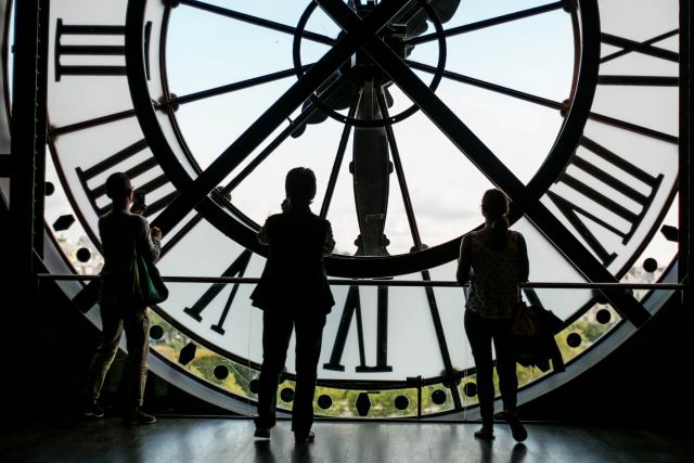 three people standing in front of a giant clock.